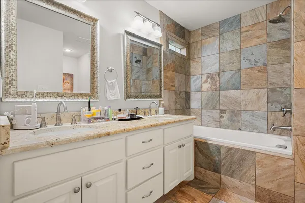 a bathroom with a granite countertop sink mirror and bathtub