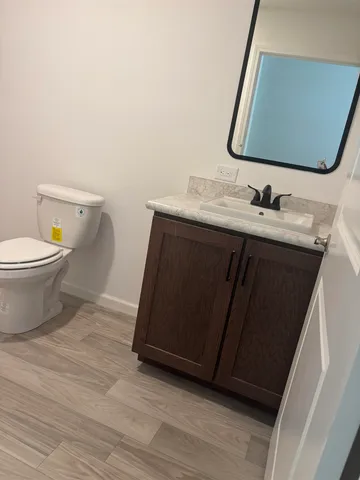 a bathroom with a granite countertop toilet sink and mirror