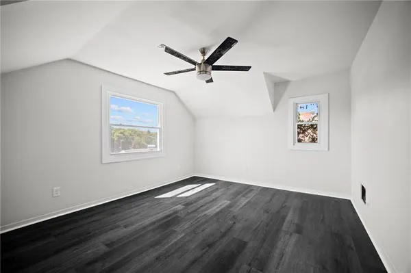 a view of a room with wooden floor ceiling fan and windows
