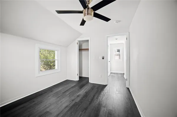an empty room with wooden floor and a ceiling fan