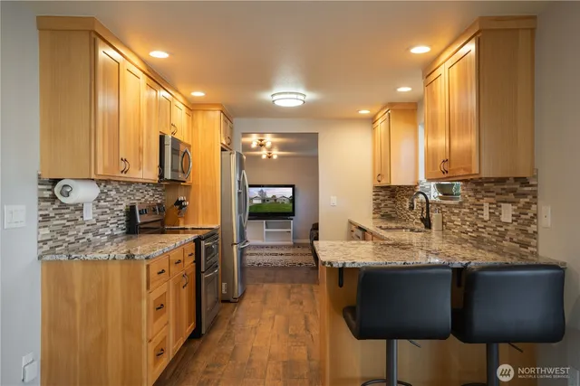 a kitchen with stainless steel appliances granite countertop wooden cabinets a stove top oven a sink and dishwasher