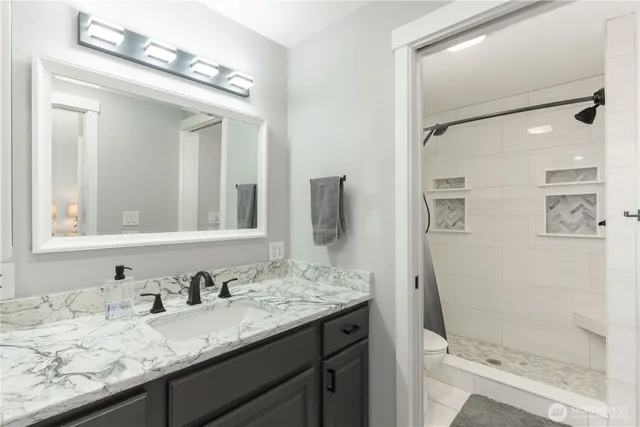 a bathroom with a granite countertop sink vanity mirror and shower