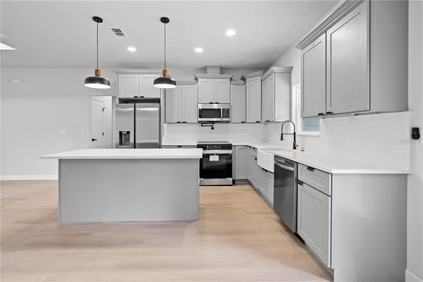 a large kitchen with stainless steel appliances kitchen island granite countertop a sink a counter top space and cabinets