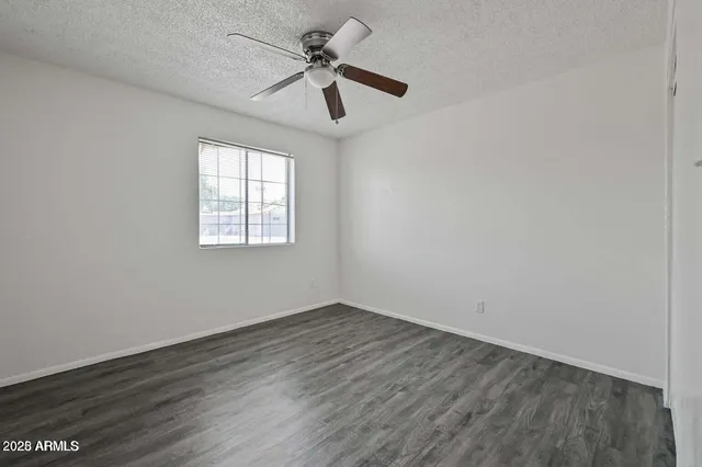 an empty room with wooden floor fan and windows
