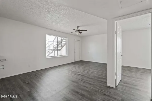 an empty room with wooden floor chandelier fan and windows
