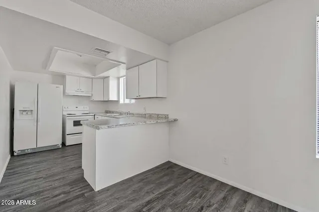 a kitchen with cabinets appliances wooden floor and a window