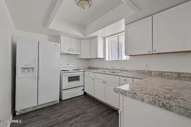 a kitchen with granite countertop white cabinets and white appliances