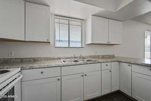 a kitchen with granite countertop white cabinets and a sink