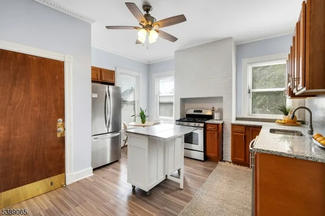 a kitchen with stainless steel appliances a stove a refrigerator a sink a oven with a dining table and chairs