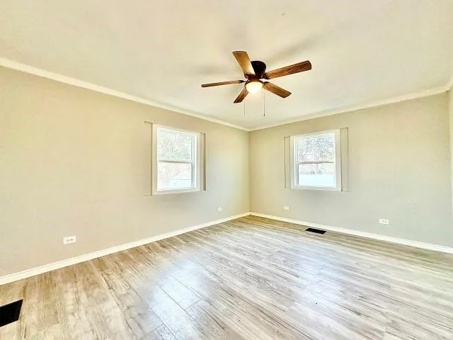 a view of empty room with wooden floor and fan