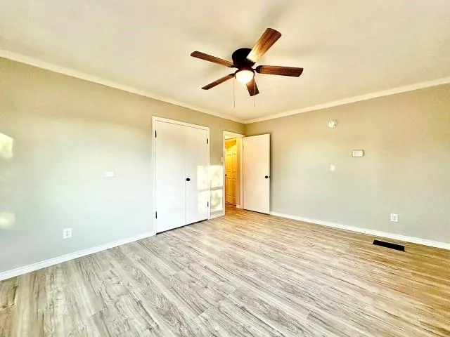 a view of a big room with wooden floor and a ceiling fan