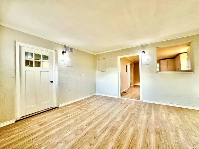a view of empty room with wooden floor and entryway