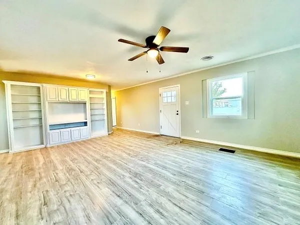 a view of an empty room with a window and wooden floor