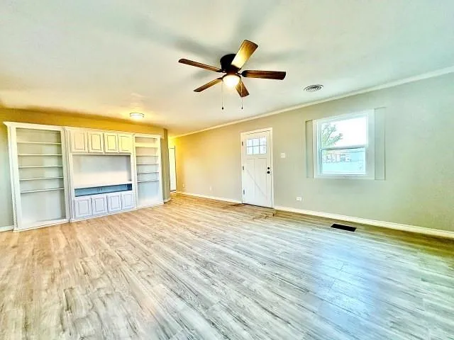 a view of an empty room with a window and wooden floor