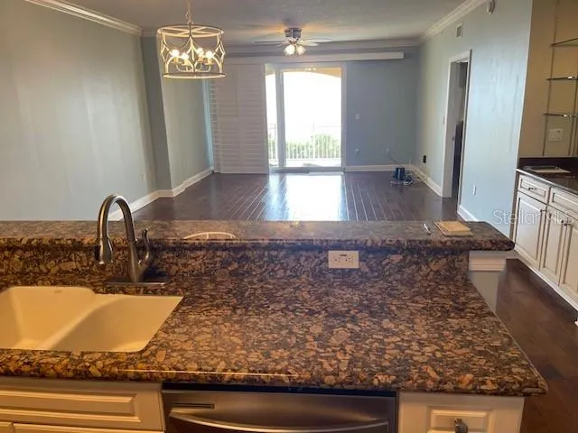 a kitchen with kitchen island granite countertop a sink and a stove top oven