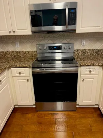 a kitchen with granite countertop a stove and a microwave