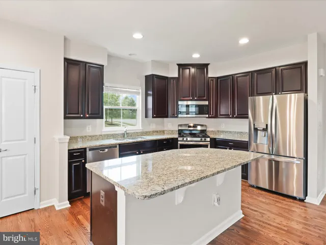 a kitchen with stainless steel appliances granite countertop a refrigerator a stove a sink and a microwave