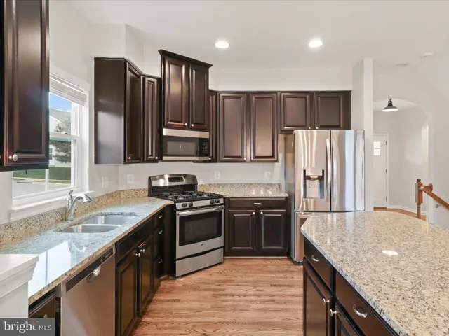 a kitchen with stainless steel appliances granite countertop refrigerator stove microwave and sink