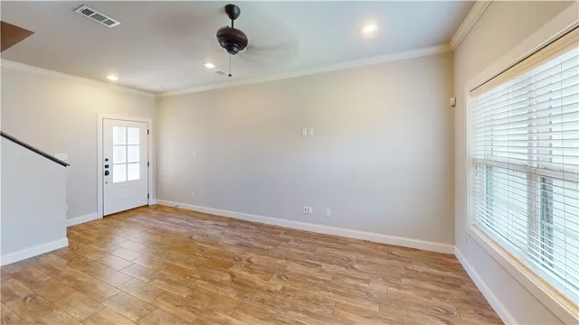 an empty room with wooden floor and windows