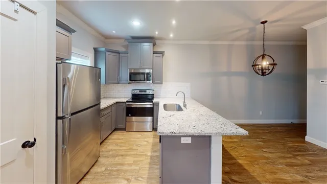 a kitchen with stainless steel appliances kitchen island granite countertop a refrigerator a stove and a sink