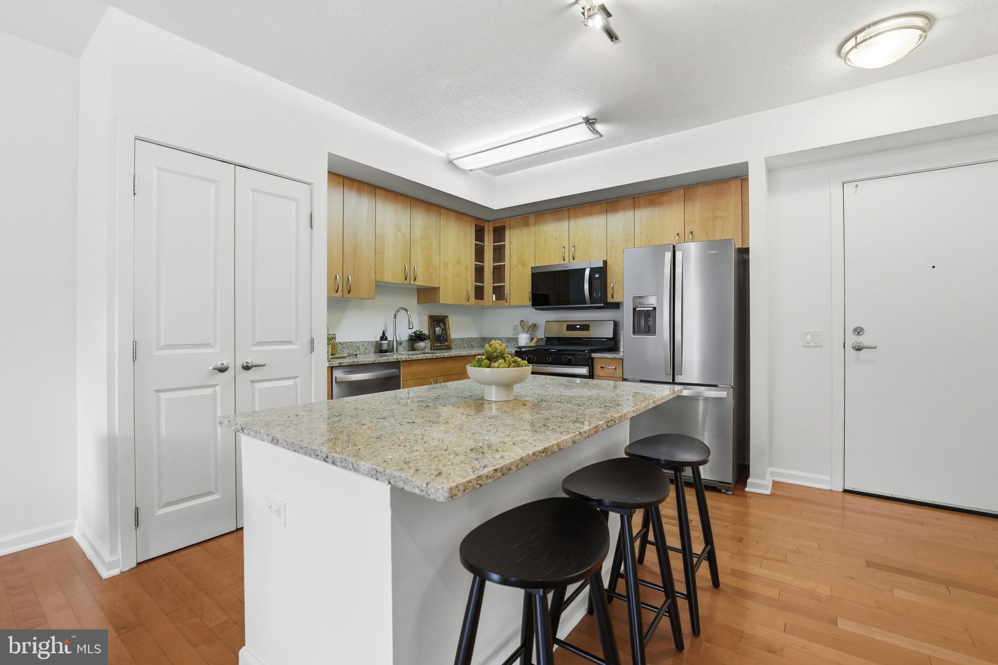 440 L Street Northwest, Unit 809 Washington, DC 20001 - Photo 9 of 50 a kitchen with stainless steel appliances granite countertop a refrigerator a stove a sink dishwasher and microwave with wooden floor