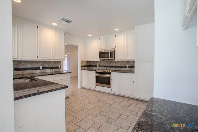 a kitchen with stainless steel appliances granite countertop a stove and a refrigerator