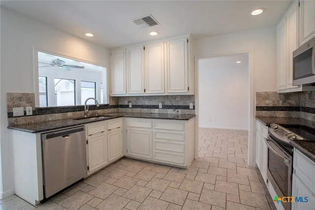 a kitchen with granite countertop a sink a stove and cabinets