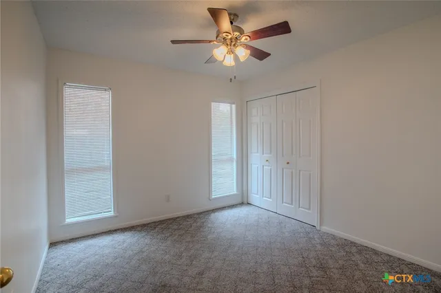 an empty room with closet and a chandelier fan