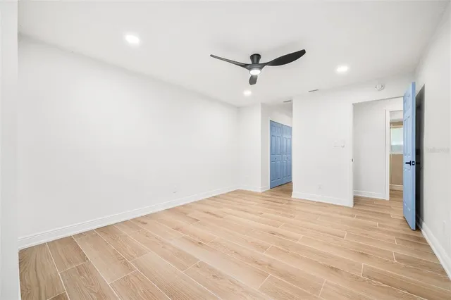 a view of empty room with wooden floor and fan