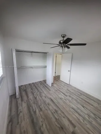 a view of empty room with wooden floor and ceiling fan