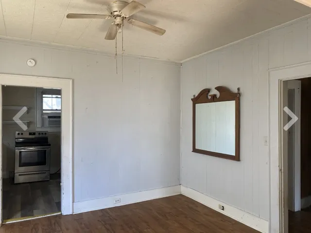 a view of a hallway with wooden floor and a bathroom