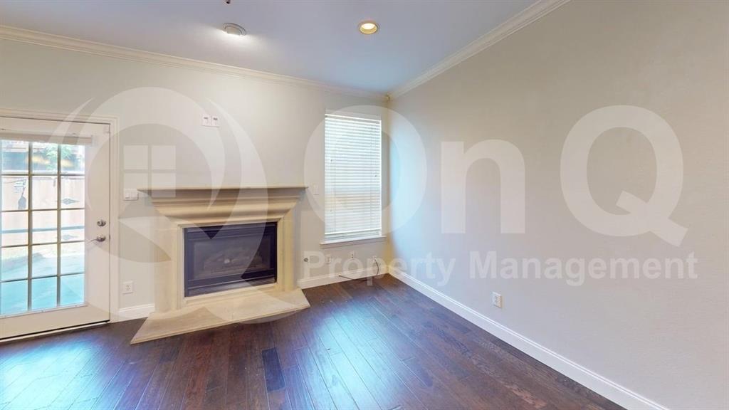 18240 Midway Road, Unit 1204 Dallas, TX 75287 - Photo 4 of 27 Living area featuring a detailed fireplace with a mantel, wood-finish flooring, white baseboards, and a glass-paneled door