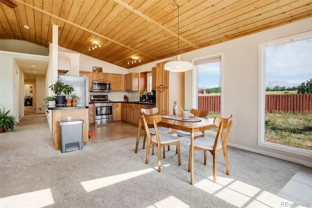 a dining hall with stainless steel appliances a dining table wooden floor and a large window