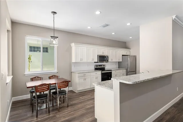 a kitchen with granite countertop a sink wooden floor and stainless steel appliances