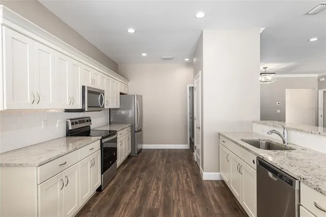 a kitchen with stainless steel appliances granite countertop white cabinets granite counter tops and a window