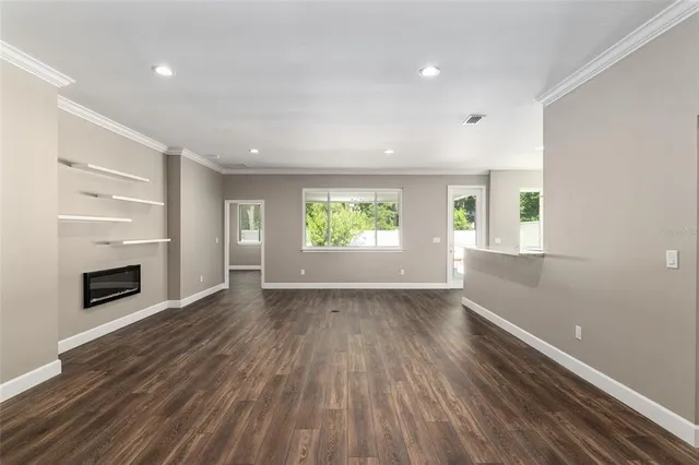 an empty room with wooden floor fireplace and windows