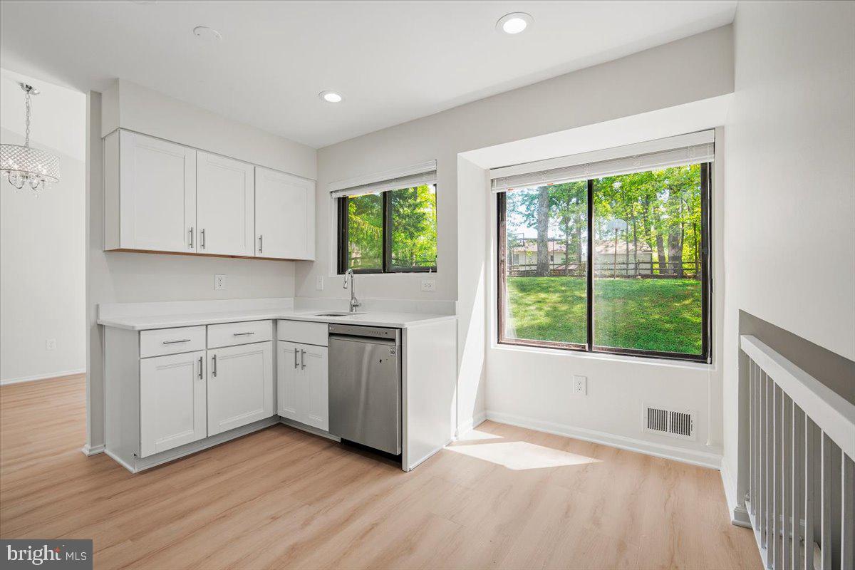 3912 Gelding Lane Olney, MD 20832 - Photo 9 of 62 a kitchen with white cabinets a sink and dishwasher with wooden floor