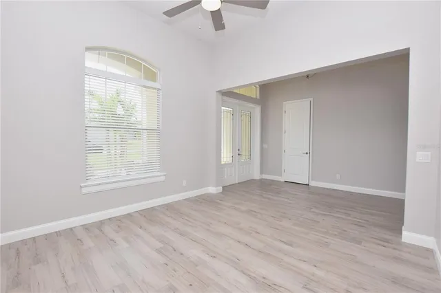 a view of an empty room with window and wooden floor