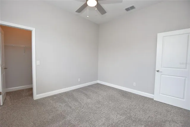 an empty room with a ceiling fan and a window
