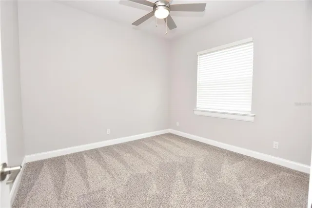 an empty room with a ceiling fan and a window