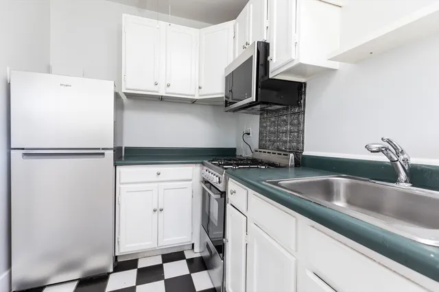 a kitchen with stainless steel appliances granite countertop a refrigerator sink and white cabinets
