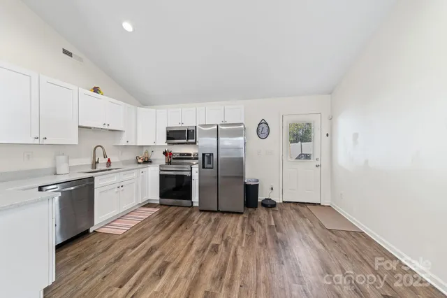 a kitchen with a refrigerator a stove top oven and wooden floor
