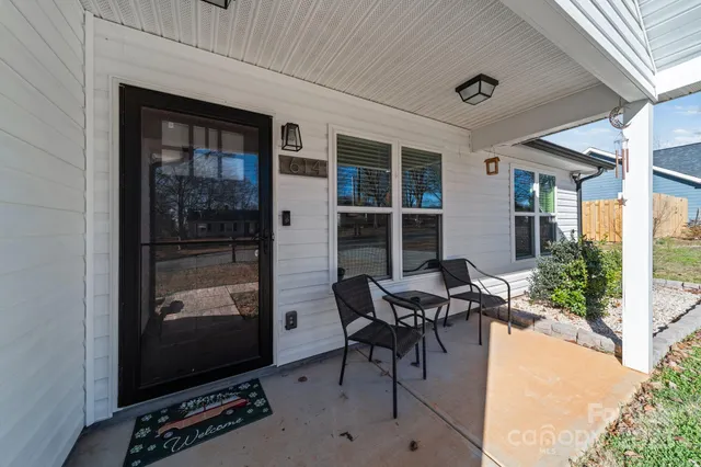 a patio with table and chairs and potted plants