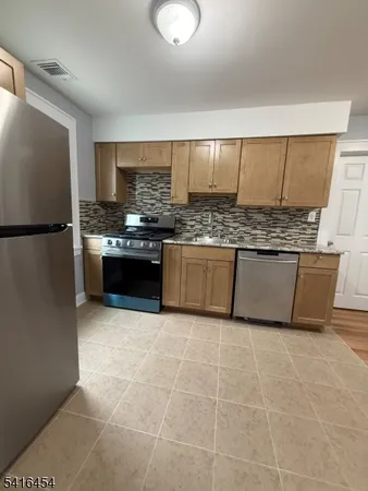 a kitchen with stainless steel appliances granite countertop a stove a sink and a refrigerator