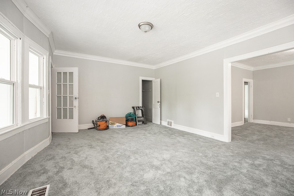 1000 Eddy Road Cleveland, OH 44108 - Photo 6 of 38 Spare room featuring carpet floors, crown molding, and a textured ceiling