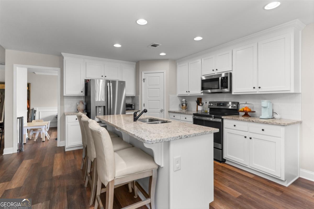 187 Loch Way Eatonton, GA 31024 - Photo 13 of 49 a kitchen with stainless steel appliances granite countertop a microwave a stove a sink a refrigerator and white cabinets with wooden floor
