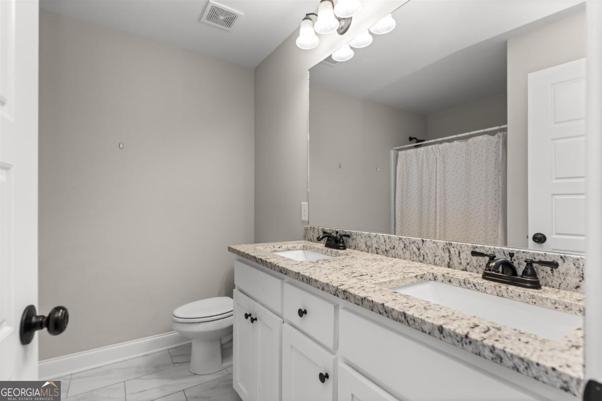 187 Loch Way Eatonton, GA 31024 - Photo 22 of 49 a bathroom with a granite countertop sink a toilet and a mirror
