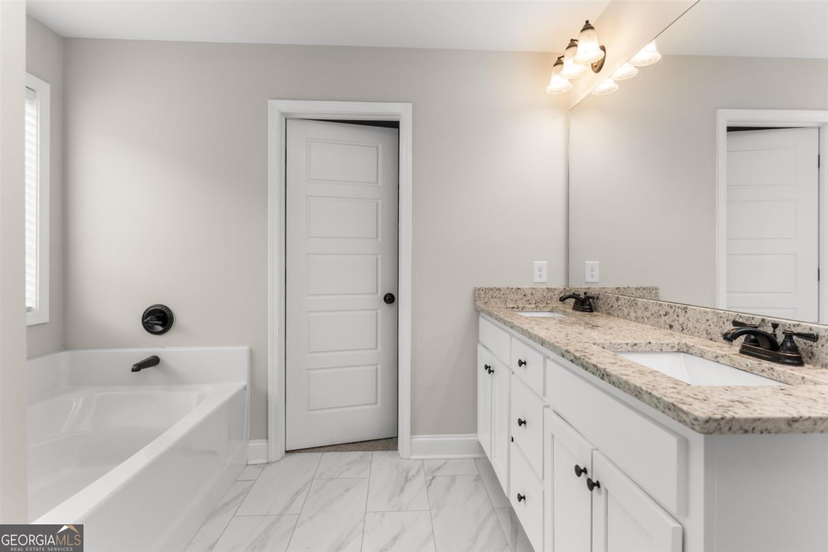 187 Loch Way Eatonton, GA 31024 - Photo 23 of 49 a spacious bathroom with a granite countertop sink a mirror and bathtub