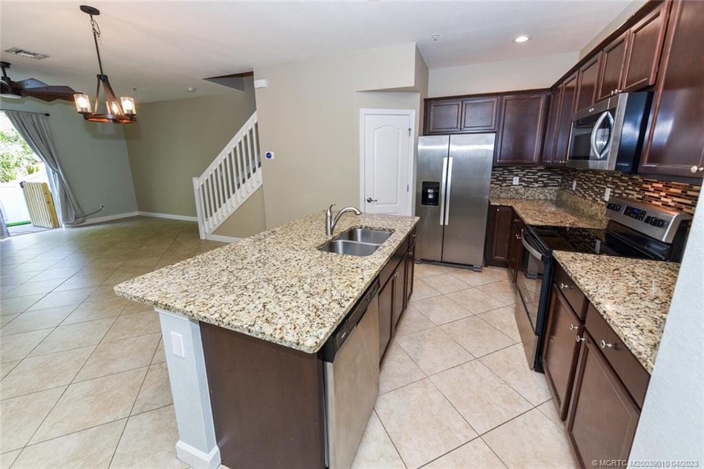 9726 Southwest Purple Martin Way Stuart, FL 34997 - Photo 6 of 30 a kitchen with kitchen island granite countertop wooden cabinets a refrigerator and a stove