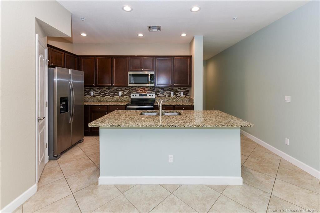 9726 Southwest Purple Martin Way Stuart, FL 34997 - Photo 7 of 30 a kitchen with kitchen island stainless steel appliances a sink stove and refrigerator